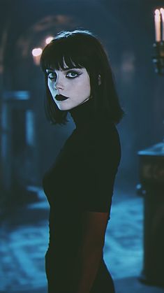 a woman with dark makeup and black hair standing in front of a candle lit room