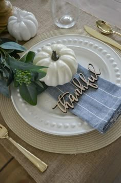 a white plate topped with a wooden name on top of a table next to gold utensils