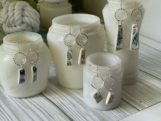 several white jars with silver charms on them sitting on a table next to some rope