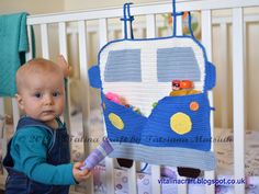 a baby standing next to a crib holding a toothbrush