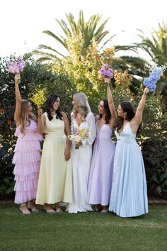 a group of women standing next to each other holding flowers