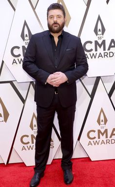 a man in a suit and tie standing on the red carpet at an awards event