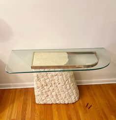 a glass table sitting on top of a hard wood floor next to a white wall