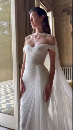 a woman in a white wedding dress is posing for the camera