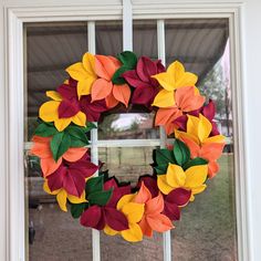 a wreath made out of paper leaves sitting on a window sill