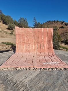 a pink blanket sitting on top of a cement slab in the middle of a field