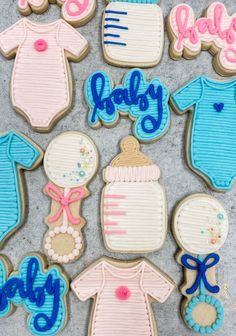 baby shower cookies decorated with blue and pink icing on a gray surface, including ones that say it's a girl