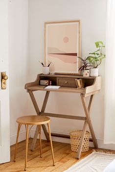 a small desk with a chair next to it and a painting on the wall behind it