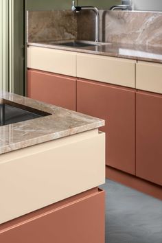 a kitchen with marble counter tops and pink cabinetry in the backround area