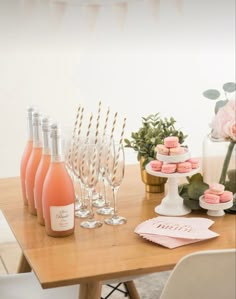 a table topped with pink cupcakes and wine glasses next to bottles of champagne