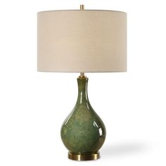 a green table lamp with a white shade on it and a gold frame around the base