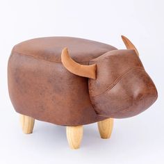 an animal shaped stool with wooden legs and a cow head on it's back