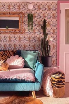 a dog laying on top of a blue couch in front of a wallpapered room