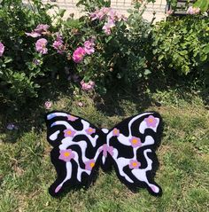 a black and white butterfly sitting on top of a green field next to pink flowers