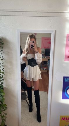 a woman taking a selfie in front of a mirror wearing a corset