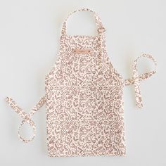 an apron with a pink and white pattern on it, next to a pair of scissors