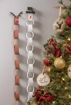 two christmas ornaments are hanging on the wall next to a decorated christmas tree with red and white ribbon