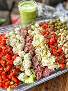 a plastic container filled with lots of different types of food next to a green smoothie