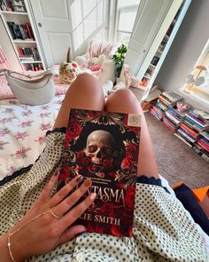 a woman laying on top of a bed holding a book