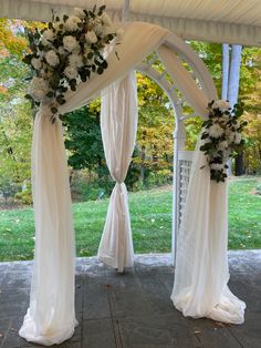 an outdoor wedding ceremony with white drapes and flowers