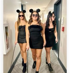 three women dressed up in mickey mouse ears and black dresses, one is holding a cane