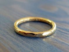 a gold wedding ring sitting on top of a wooden table