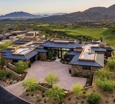 an aerial view of a home in the desert with mountains in the backgroud