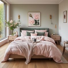 a bed with pink comforter and pillows in a bedroom next to a large window