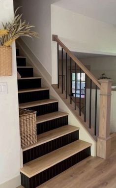 the stairs are made of wood and have black railings on each handrail, along with wicker baskets