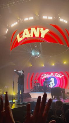 a man standing on top of a stage holding his hands up