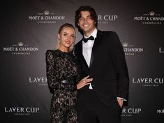 a man and woman standing next to each other on a red carpet