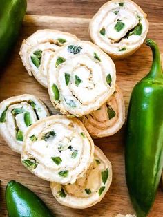 some food is laying out on a cutting board next to two green peppers and an eggplant