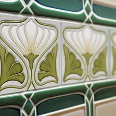 a close up view of some decorative tiles on the side of a building with green and white designs