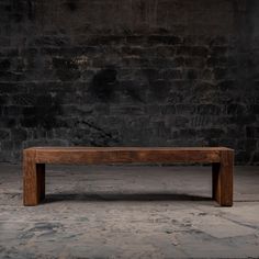 a wooden bench sitting in front of a brick wall with no one on it's legs