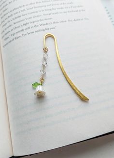 the book is open to show an image of a necklace with pearls and green leaves on it