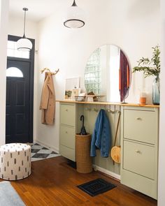 a room with a mirror, coat rack, and stool in the middle of it