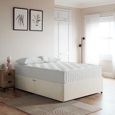 a white bed sitting on top of a wooden floor next to a dresser and window