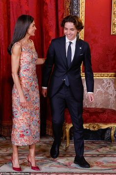 a man in a suit and tie standing next to a woman in a floral dress