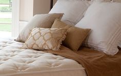 a bed with white pillows and brown blankets