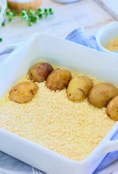 four potatoes in a white dish on a blue and white cloth