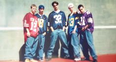 a group of young men standing next to each other in front of a cement wall