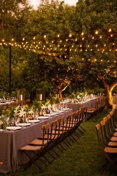 an outdoor dining area with tables and chairs set up for dinner under the shade of trees