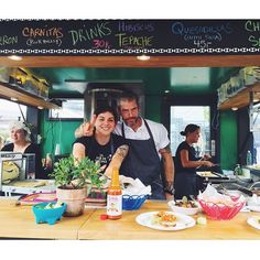 a man and woman standing in front of a table with food on it at a restaurant