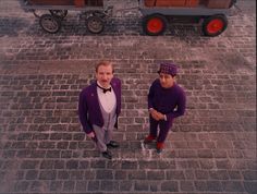 two men in purple suits and hats standing next to each other on brick walkways