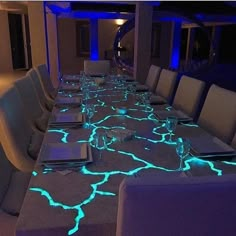 a long table is lit up with blue lights in the center and white chairs around it