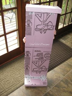 a person holding up a cardboard box with drawings on it's front and sides