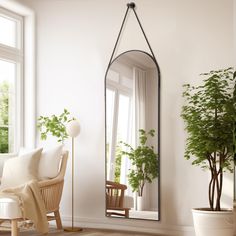 a living room with a chair, mirror and potted plant