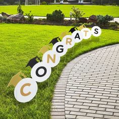 graduation party decorations on the grass in front of a brick path