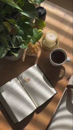 an open book sitting on top of a wooden table next to a cup of coffee