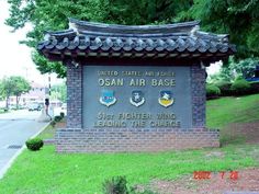 the sign for osan air base is in front of some trees